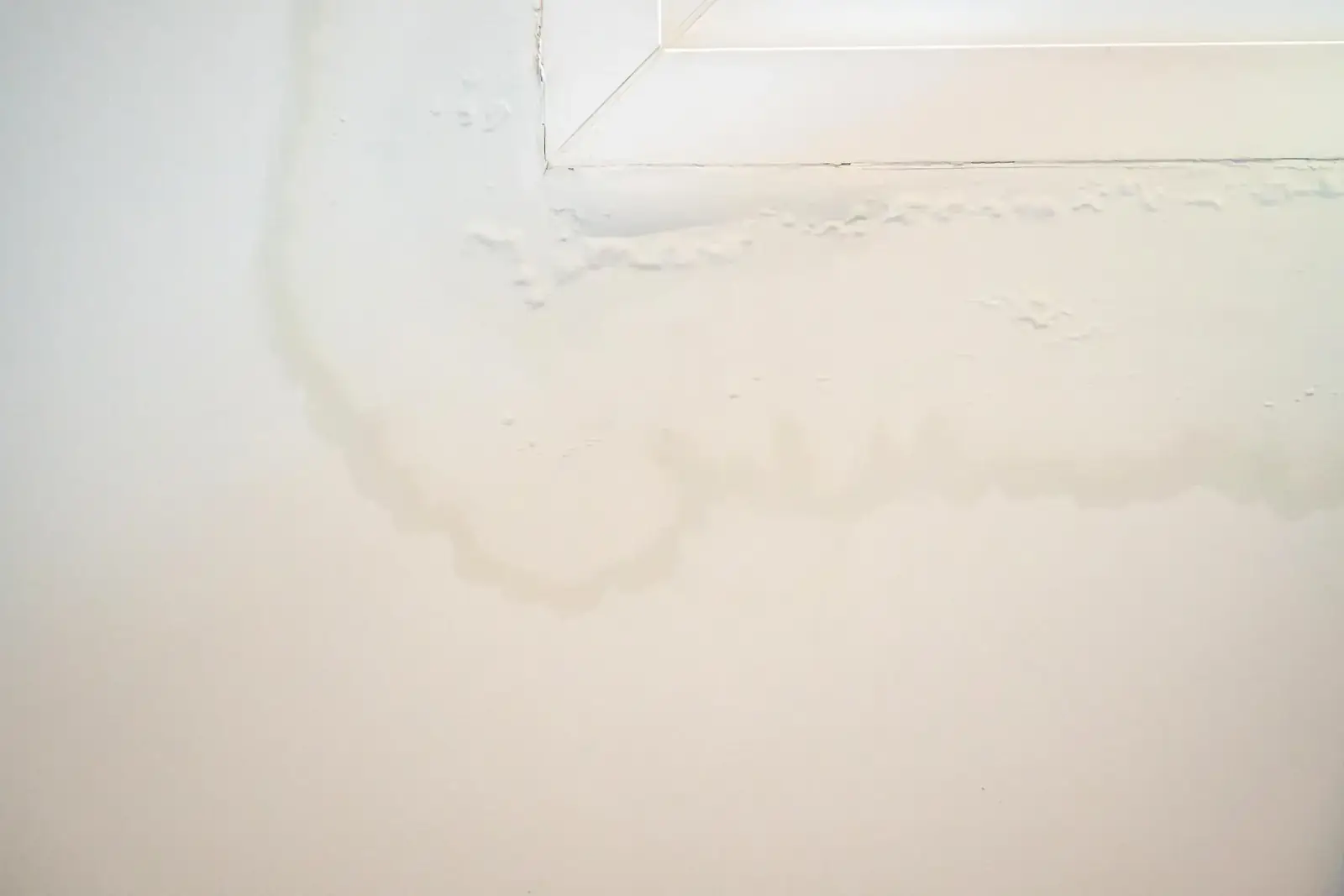 Mur de la maison près de la fenêtre avec quelques taches d'eau montrent de la peinture écaillée